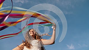 Teenage girl whirls, plays with colorful ribbons outdoors