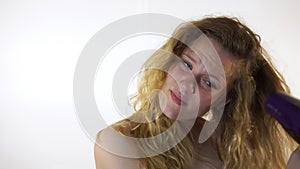 Teenage girl on a white background dries her hair with a Hairdryer.
