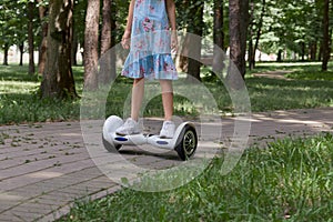 A teenage girl in white sneakers on a gyro scooter ride through the Park.