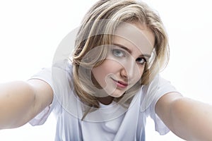 A teenage girl in a white T-shirt takes a selfie. Blogging and social networks. White background. Close-up