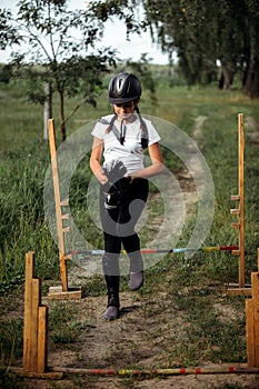 A teenage girl who is fond of hobbyhorsing jumps over obstacles