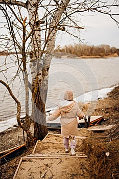 Teenage girl in winter clothes going down the stairs on the ice on the bank.