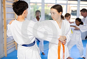 Teenage girl working on martial arts skills in pair with boy during training