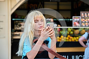 Teenage girl 16, 17 years old with a smartphone in the city.