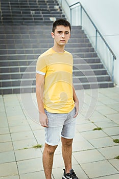 Teenage girl in yellow t-shirt and shorts looking at camera