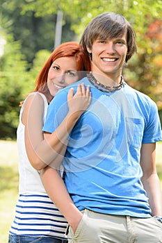 Teenage girlfriend embracing her boyfriend in park