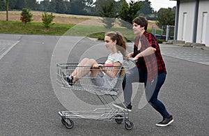 Teenage girlfriends having fun with shopping cart