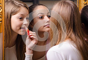 Teenage girlfriends putting make up in front of the old mirror