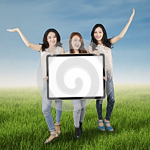 Teenage girls with billboard on meadow