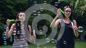 Teenage girls blowing soap bubbles in summer time
