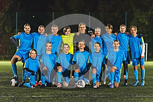 teenage girls in blue sportswear taking a team photo with their coach, full shot, stadium