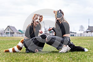 Teenage girls with cat mask and gloves doing Quadrobics. girls in a cat mask is lying on the grass.