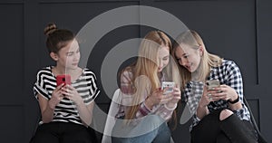 Teenage girls having fun while text messaging on mobile phones
