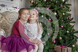 Teenage girls having fun under Christmas tree with gifts