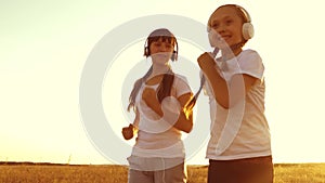 Teenage girls in headphones are engaged in jogging, laughing and smiling during physical exertion. Slow motion