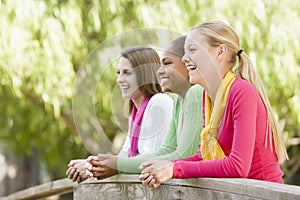 Teenage Girls Leaning On Wooden Railing