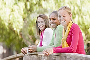 Teenage Girls Leaning On Wooden Railing