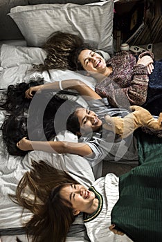 Teenage girls lying on the bed together with stuffed animal childhood and friendship concept