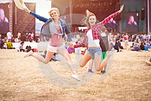Teenage girls, music festival, jumping, in front of stage