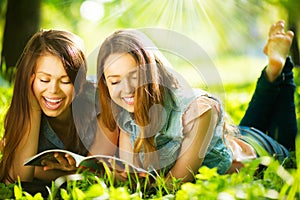 Teenage girls reading a magazine outdoors