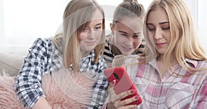 Teenage girls reading social media content on mobile phone