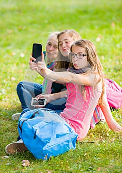 Teenage girls sitting on grass and taking selfie