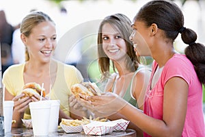 Teenage Girls Sitting Outdoors Eating Fast Food