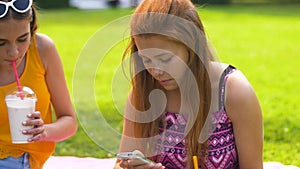 Teenage girls with smartphones and shakes in park