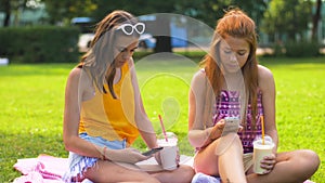 Teenage girls with smartphones and shakes in park