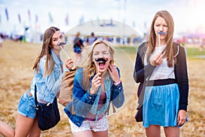 Teenage girls at summer festival with fake mustache