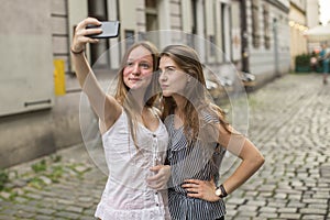 Teenage girls take pictures of themselves on the smartphone on the street.
