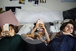 Teenage girls using smartphones on a bed in slumber party