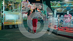 Teenage girls walking amusement park rear view. Happy best friends having fun