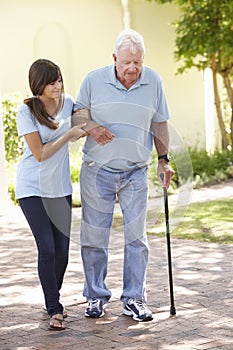 Teenage Granddaughter Helping Grandfather Out On Walk