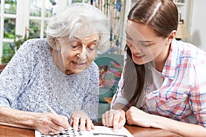 Teenage Granddaughter Helping Grandmother With Crossword Puzzle