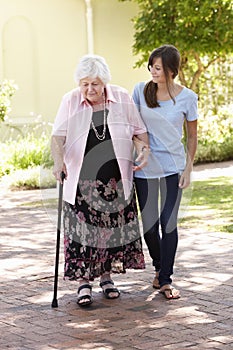 Teenage Granddaughter Helping Grandmother Out On Walk