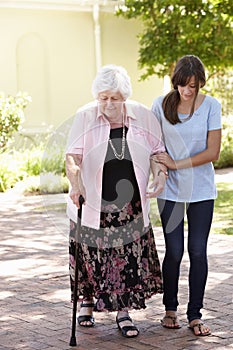 Teenage Granddaughter Helping Grandmother Out On Walk