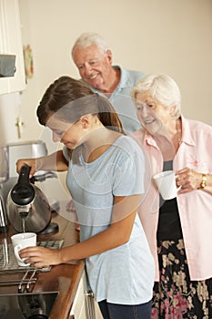 Teenage Granddaughter Sharing Cup Of Tea With Grandmother In Kitchen