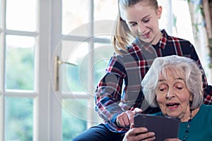 Teenage Granddaughter Showing Grandmother How To Use Digital Tab