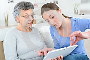 Teenage granddaughter showing grandmother how to use digital tablet