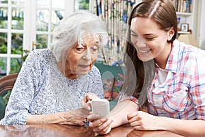 Teenage Granddaughter Showing Grandmother How To Use Mobile Phon