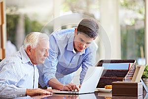 Teenage Grandson Helping Grandfather With Laptop