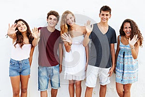 Teenage Group Leaning Against Wall Waving