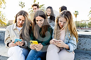 Teenage group of young people looking at smart mobile phone screen outdoors