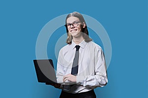 Teenage guy college student posing with laptop in hands on blue background