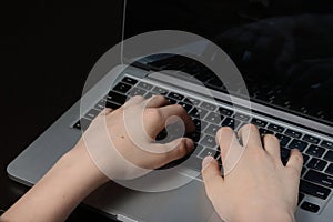 Teenage hands in close-up on a laptop keyboard, symbolizing proficiency in computing and digital literacy skills photo