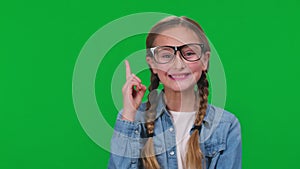 Teenage intelligent girl in eyeglasses thinking gesturing idea looking at camera smiling on green screen. Portrait of