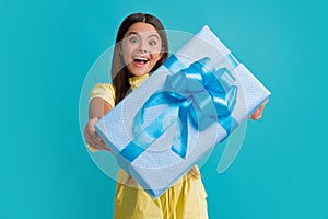 Teenage kid with present box. Teen girl giving birthday gift. Present, greeting and gifting concept. Excited face