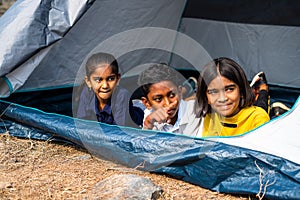 Teenage kids inside camping tent busy taking about nature at summer camp on hill top - concept of leisure activities