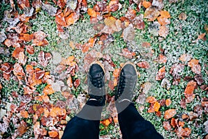 Teenage legs in boots on fallen leaves and snow